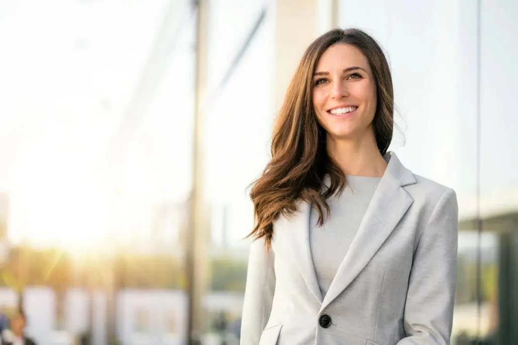 Mujer profesional sonriente con traje gris, representando el perfil de los estudiantes del Global Executive MBA de Euncet Business School.