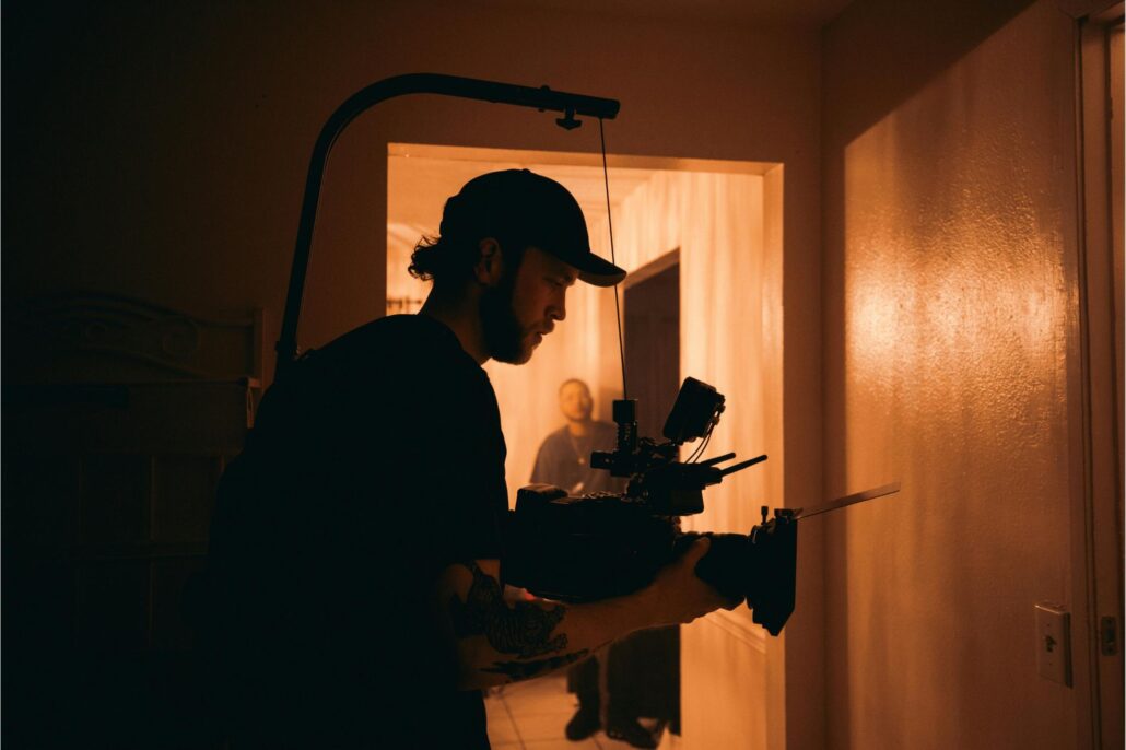 Camarógrafo grabando una escena en interiores con iluminación cálida y equipo profesional de filmación