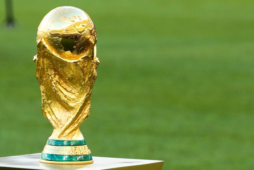 Primer plano del trofeo dorado de la Copa Mundial de la FIFA posado sobre una plataforma en un campo de fútbol