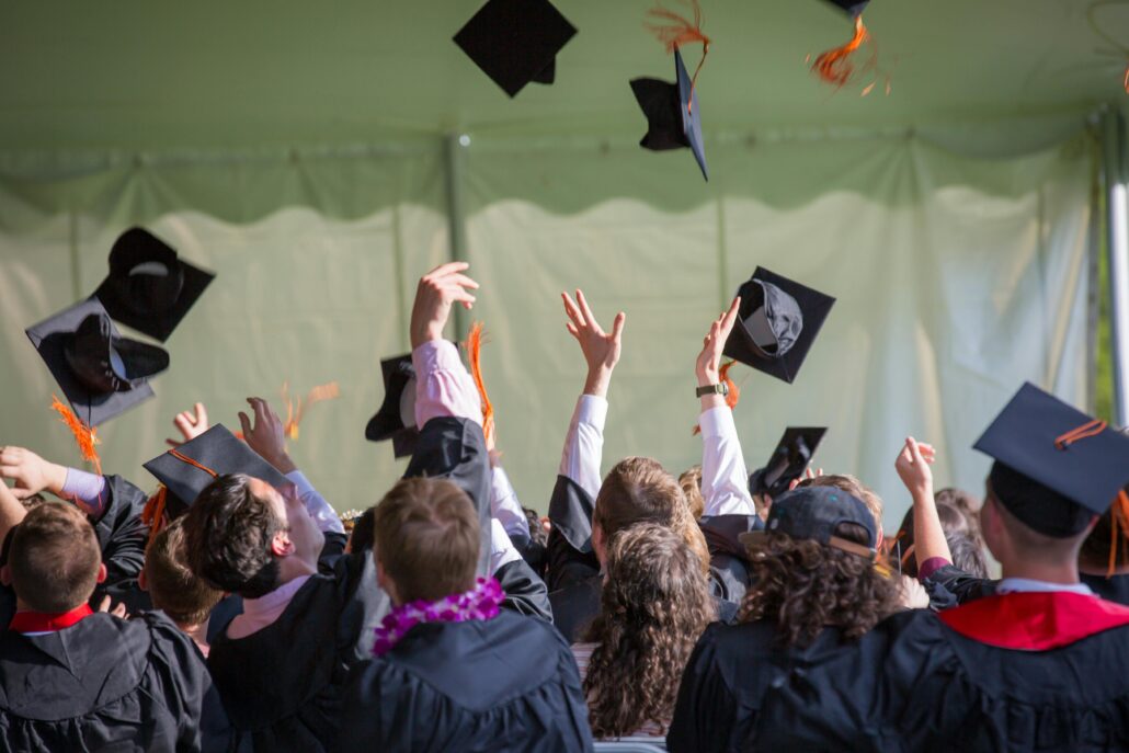 Estudiantes lanzando sus birretes al aire durante una ceremonia de graduación.